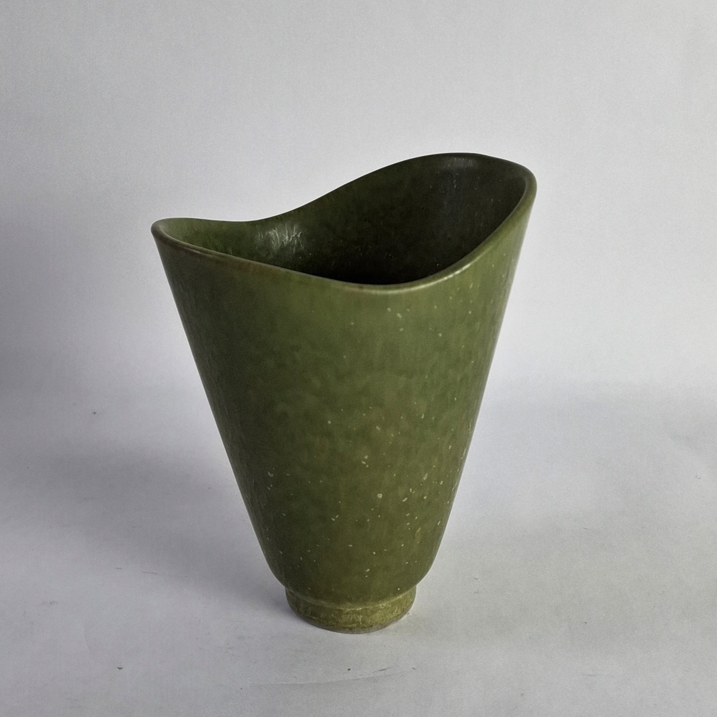 An asymmetrical stoneware vase with a green glaze.