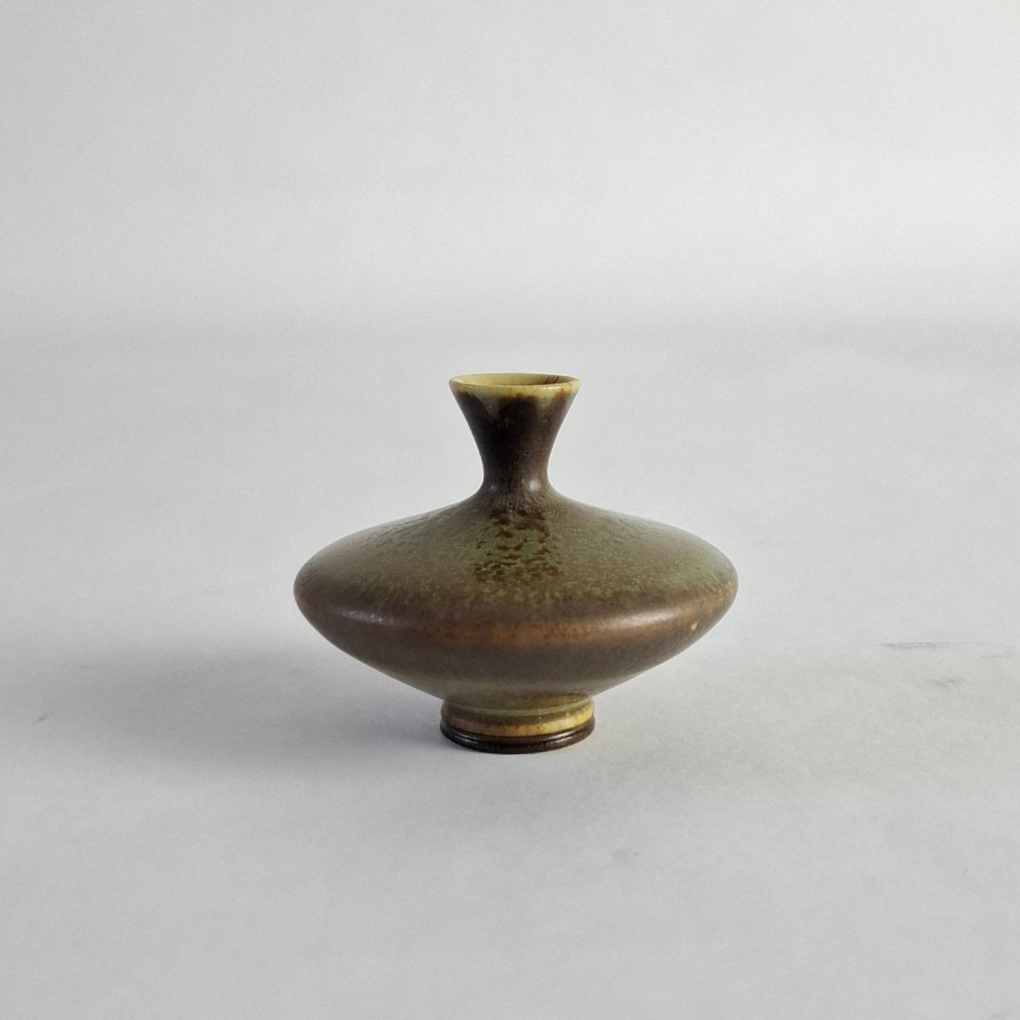 A miniature discus-shaped vase with a green and brown haresfur glaze, signed and dated underneath.