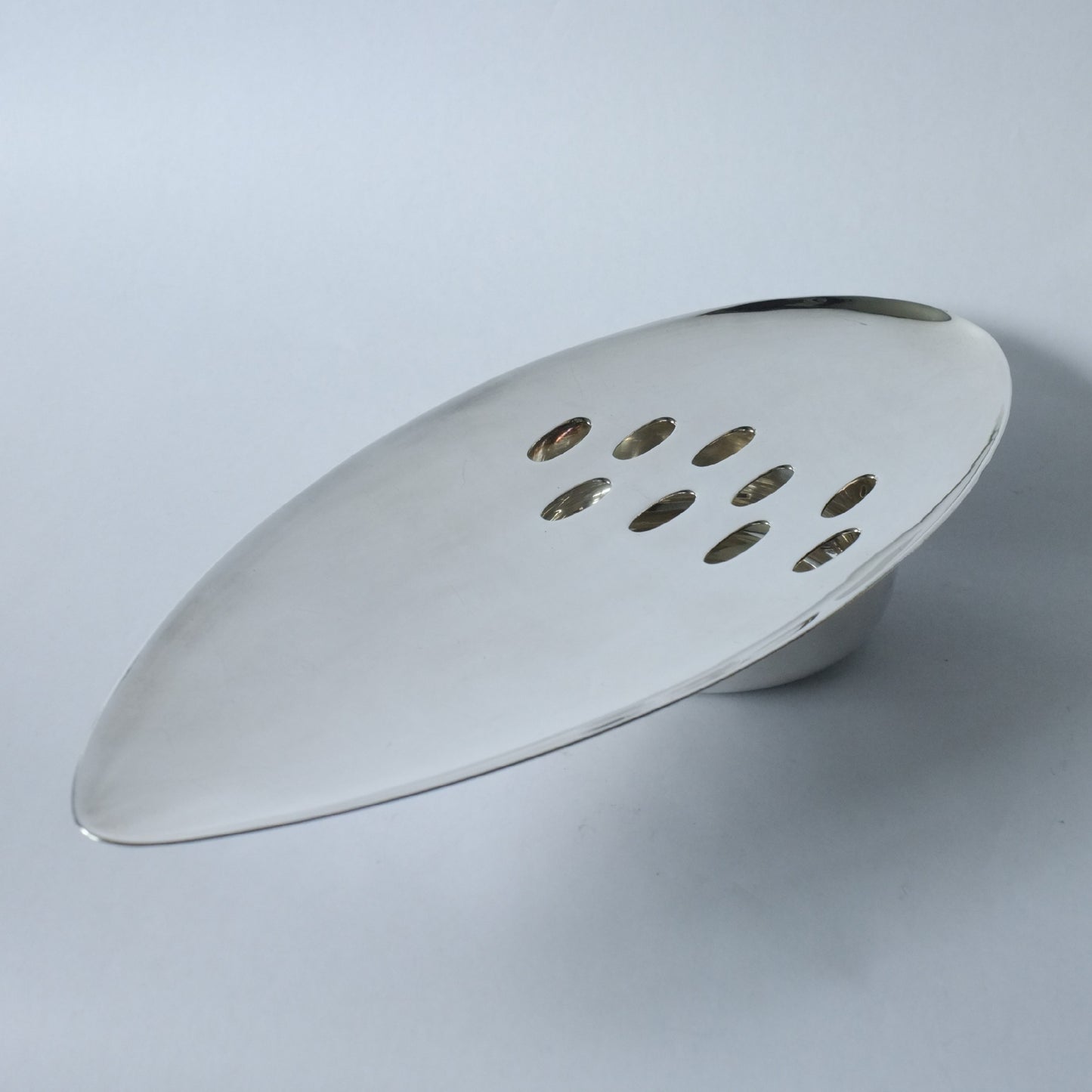 A silver plated table centrepiece with an elongated oval shape and multiple circular perforations.