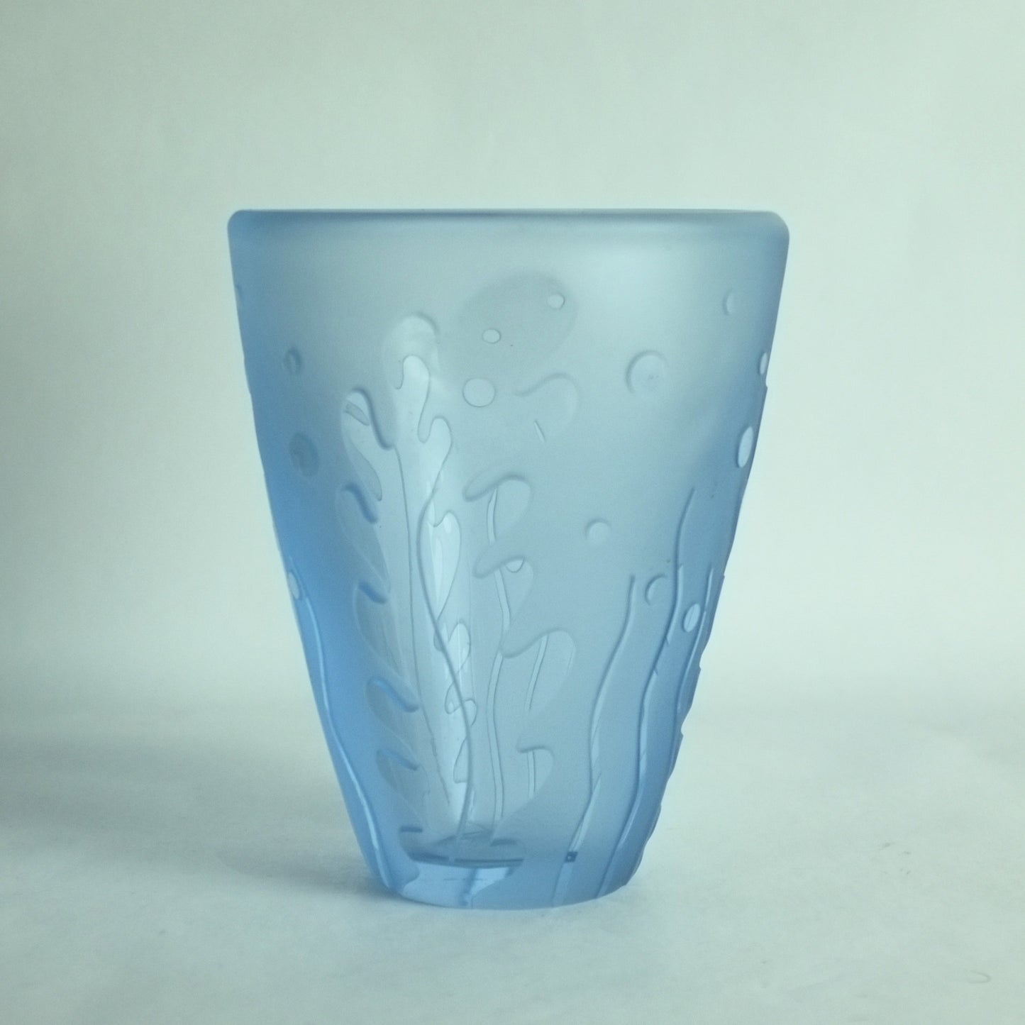 An acid etched blue glass vase with underwater seaweed designs in high relief.