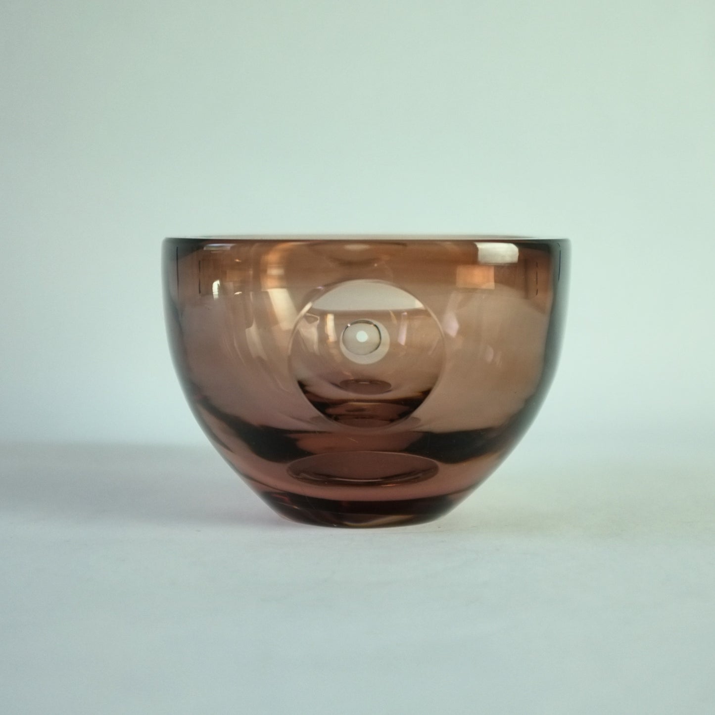 A square pinky brown glass bowl with a clear cut lens decoration.