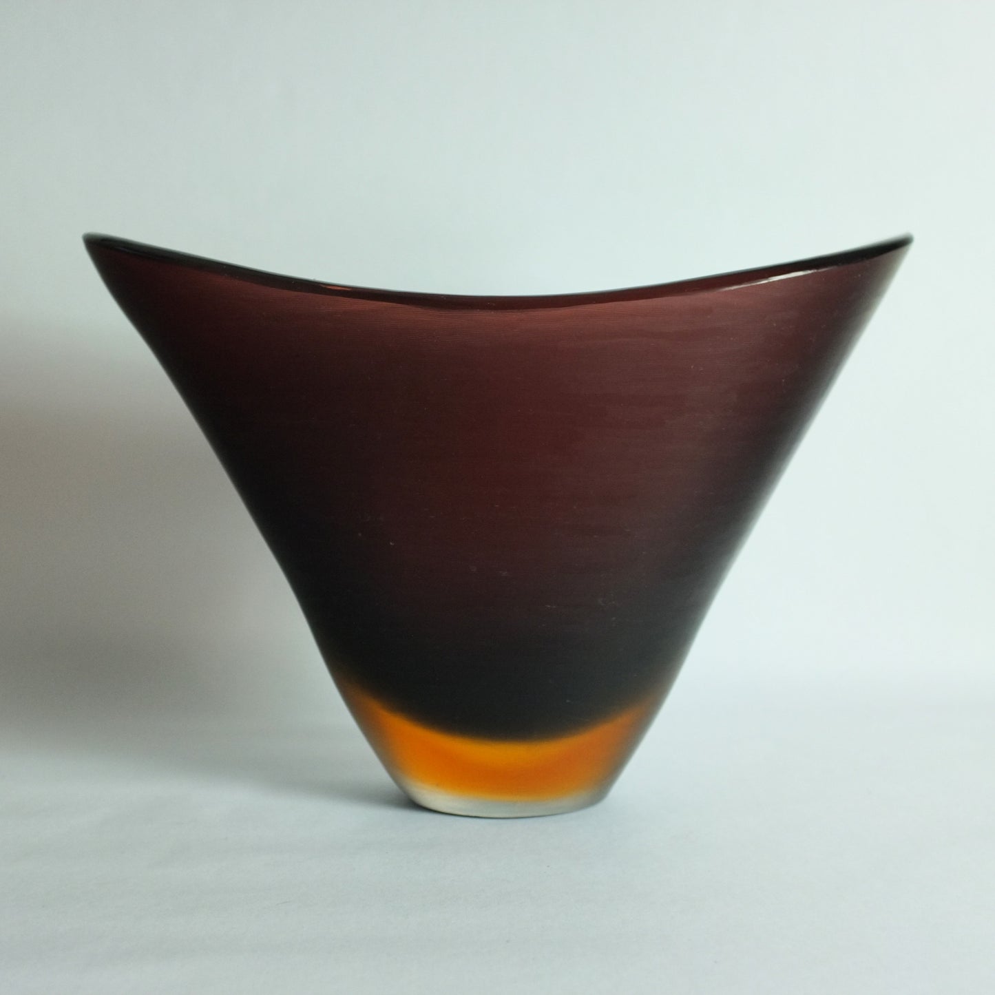 A large flattened V shaped vase with deep "prugnolo" color overlaid in orange and clear and featuring fine etched lines across the surface.