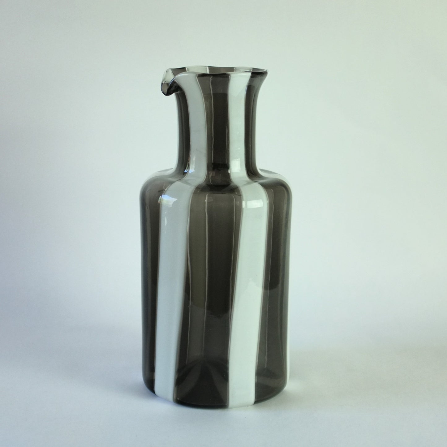 Glass carafe with wide vertical bands of alternating white and grey.