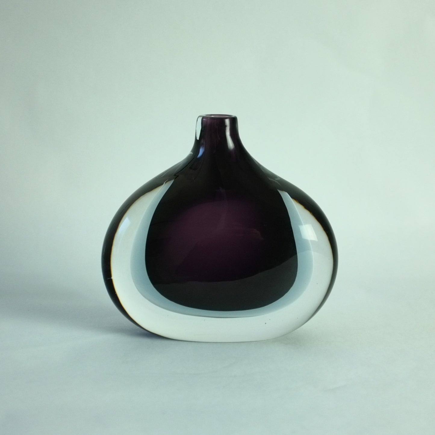 A double cased glass vase with deep purple, grey, and clear colors, free blown with a teardrop shape.