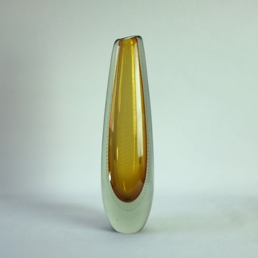 A tall free-blown glass vase with trapped air bubbles, featuring a yellow core and clear glass casing.