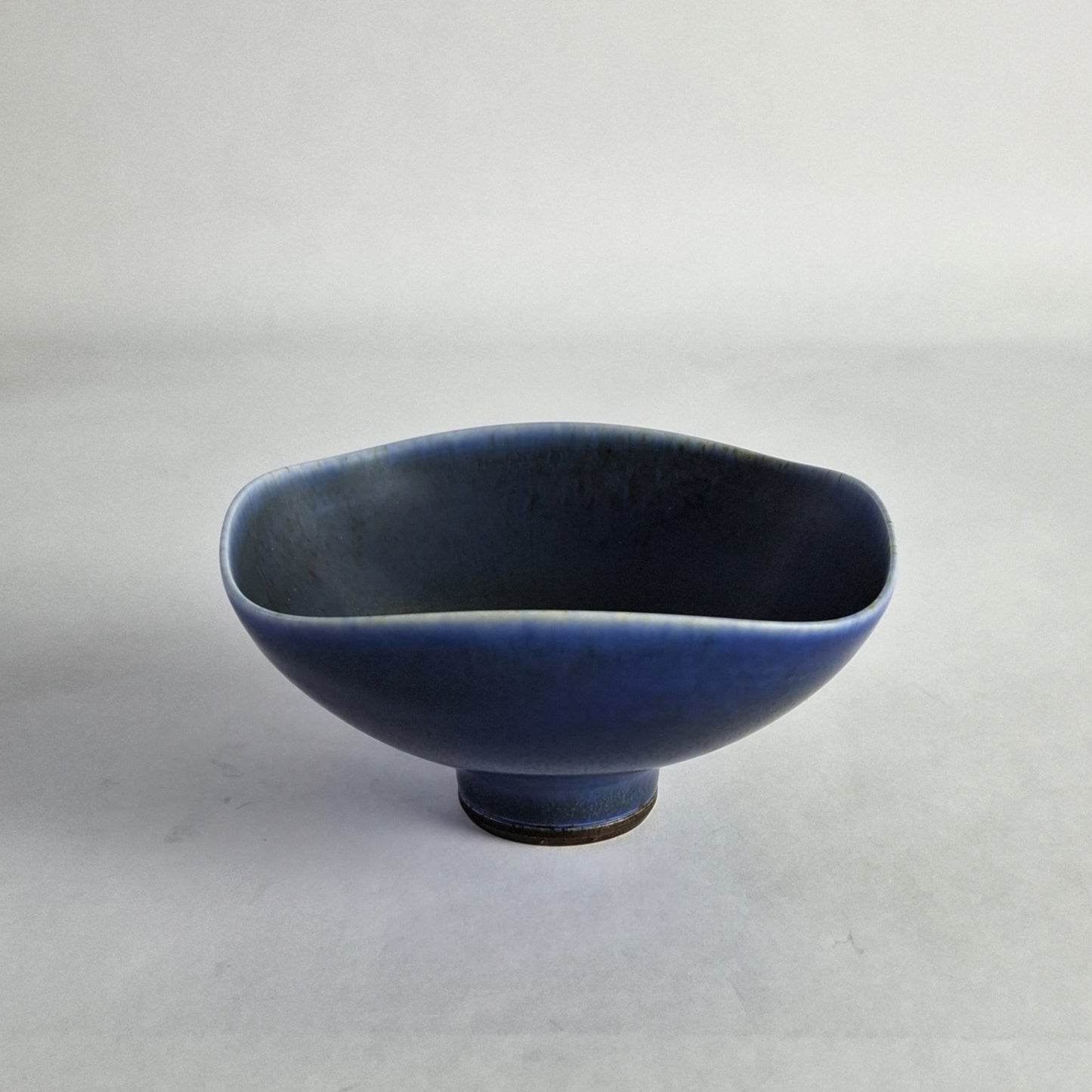 A square ceramic bowl with rounded corners and a blue haresfur glaze.