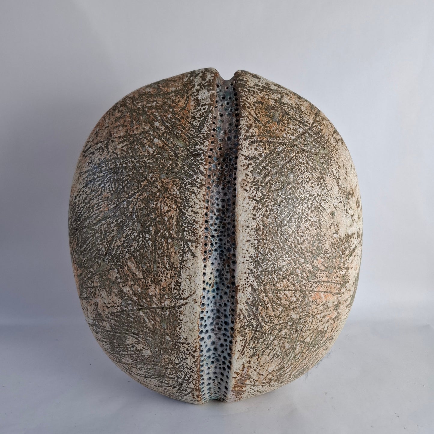 A monumental flattened ovoid stoneware vase with central vertical groove and heavily textured and glazed surface.