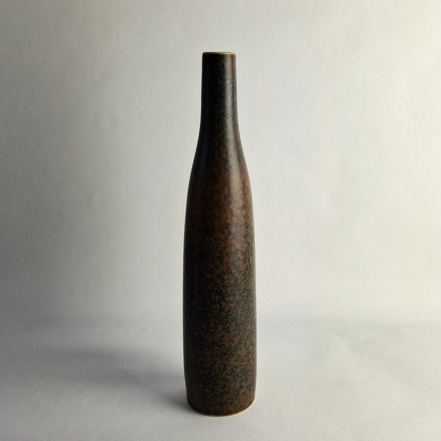 A tall stoneware vase with mottled brown glaze.