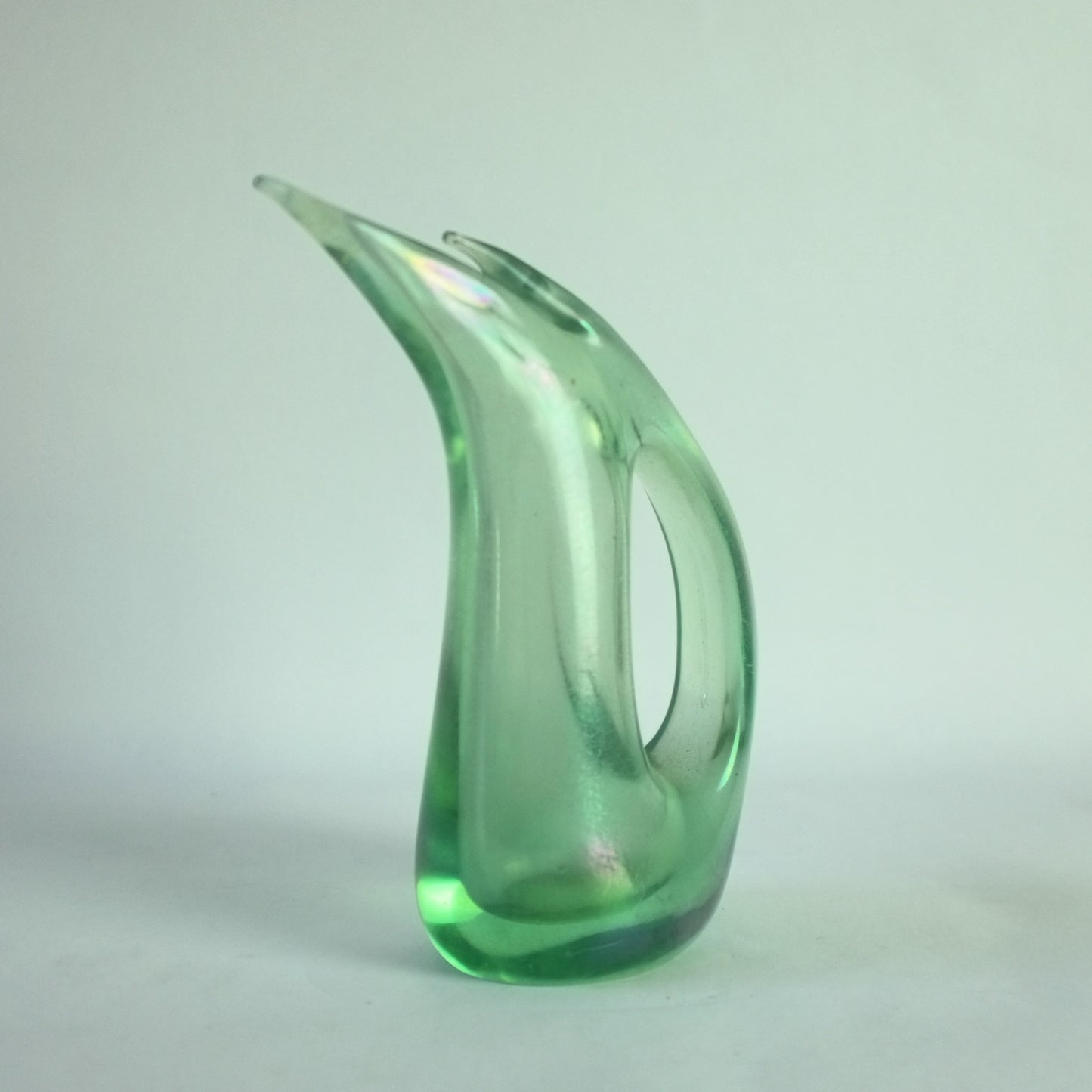 A light green, abstractly shaped glass vase with an iridized surface.