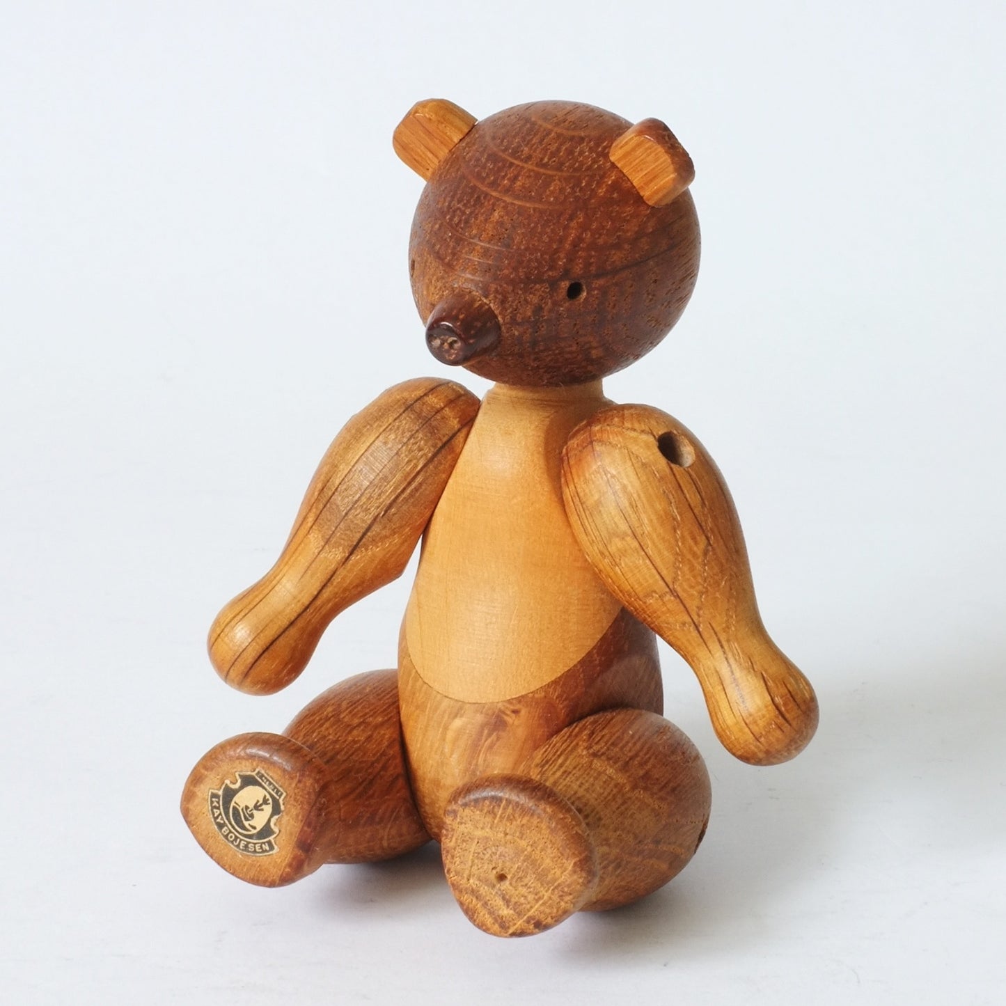 A wooden toy bear with semi-articulated limbs.