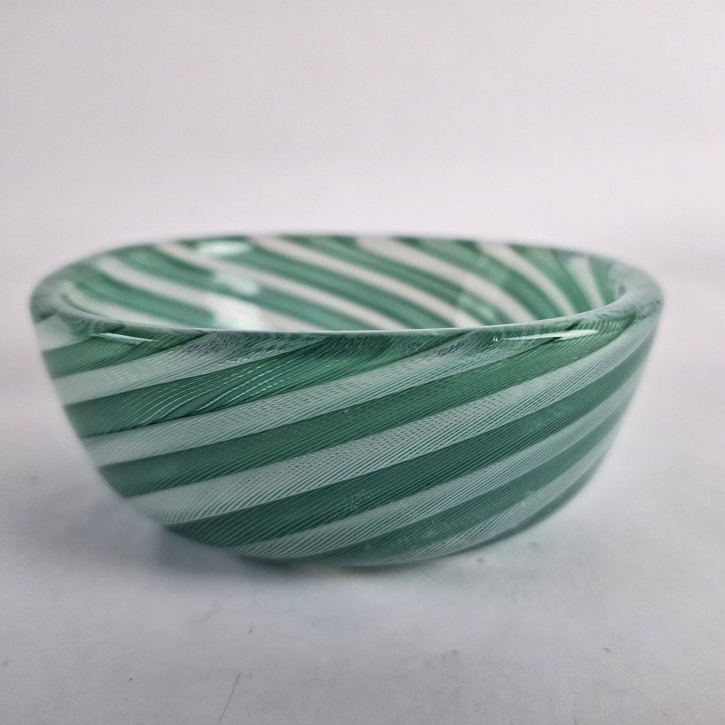 A square, glass bowl with a pattern of alternating white and green zanfirico canes.