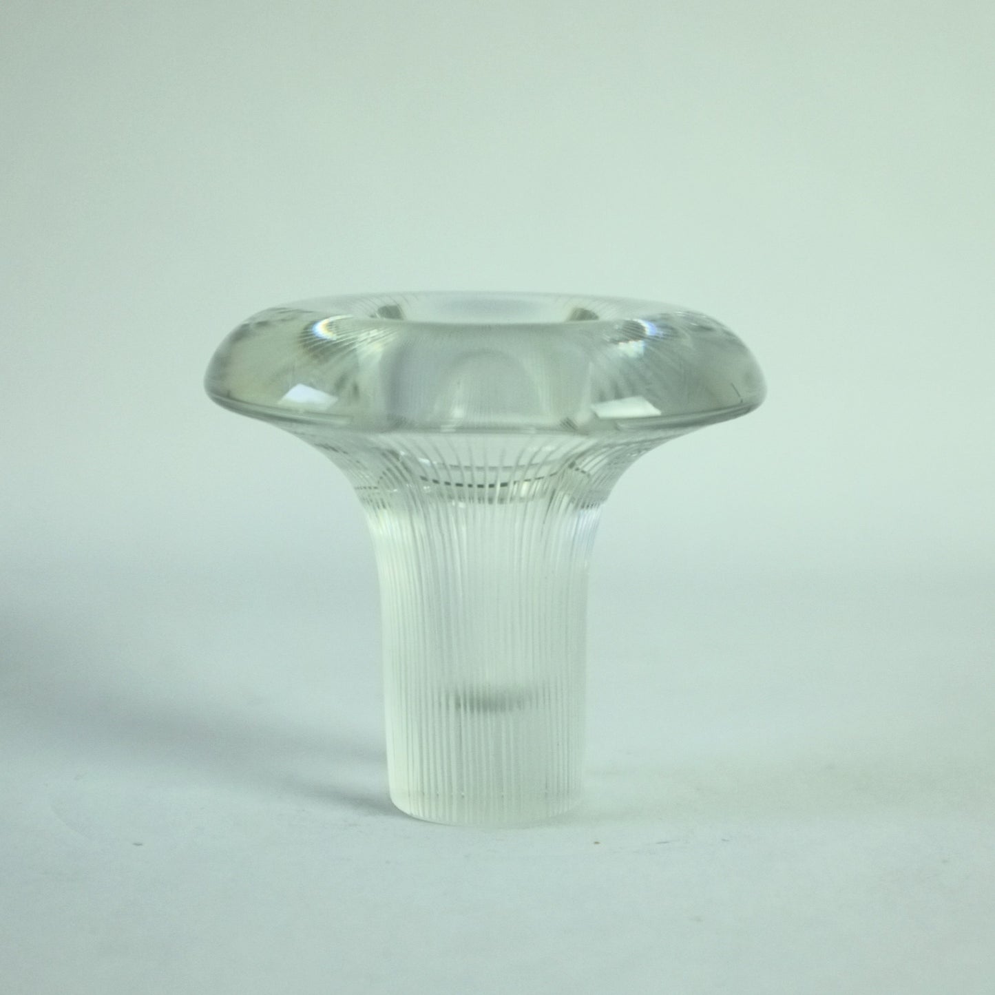 A clear glass vase with vertical lines engraved from the base to the rim, displaying a distinctive shape of a mushroom.