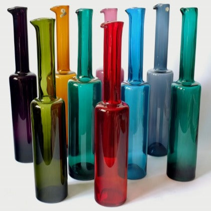 A collection of nine colored glass bottles, all with long necks, designed by Nanny Still for Riihimaki. 