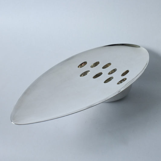 A silver plated table centrepiece with an elongated oval shape and multiple circular perforations.