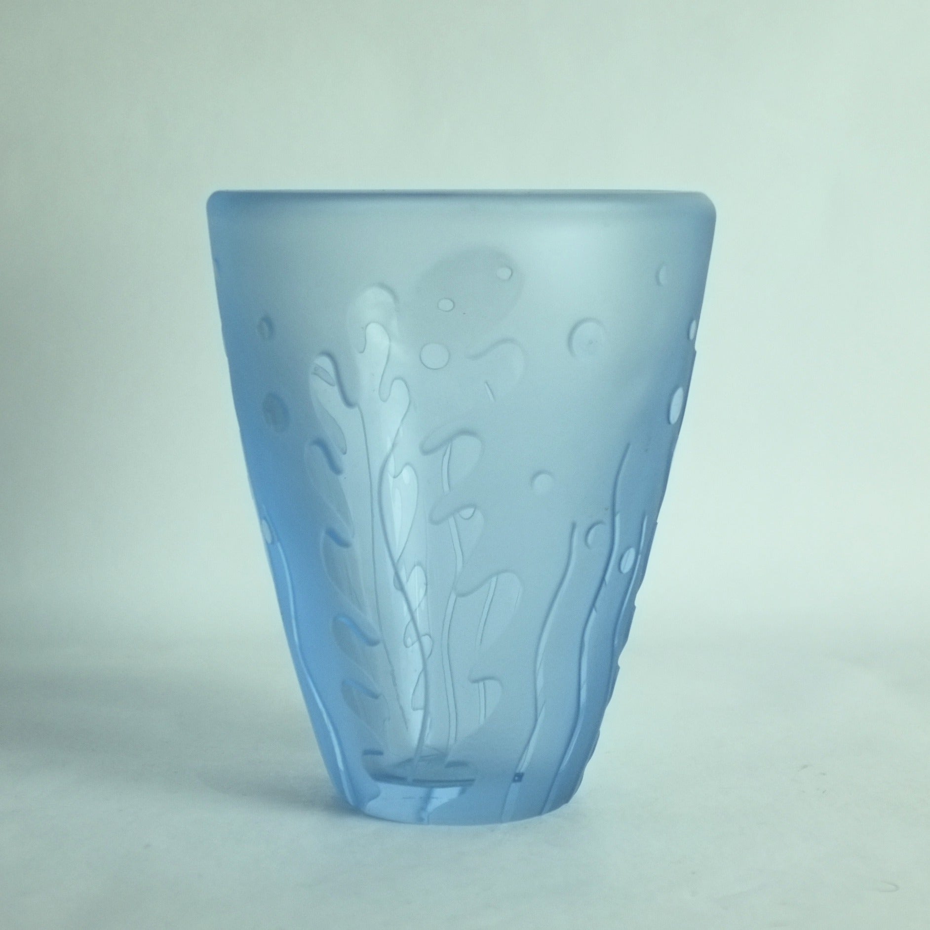 An acid etched blue glass vase with underwater seaweed designs in high relief.