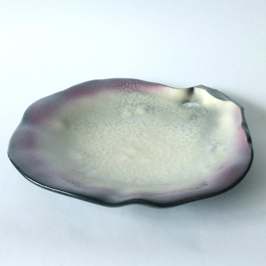 A shell-shaped faience dish with a pearlescent glaze and deep purple/black edge byPol Chambost, France.
