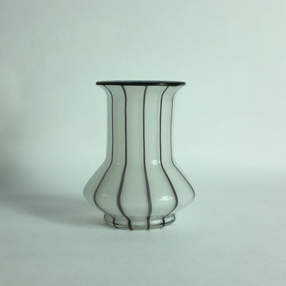 A white glass vase with black applied stripes and a black rim.