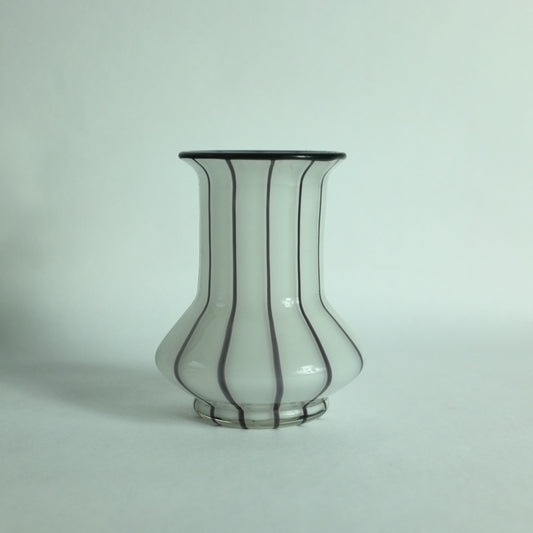 A white glass vase with black applied stripes and a black rim.