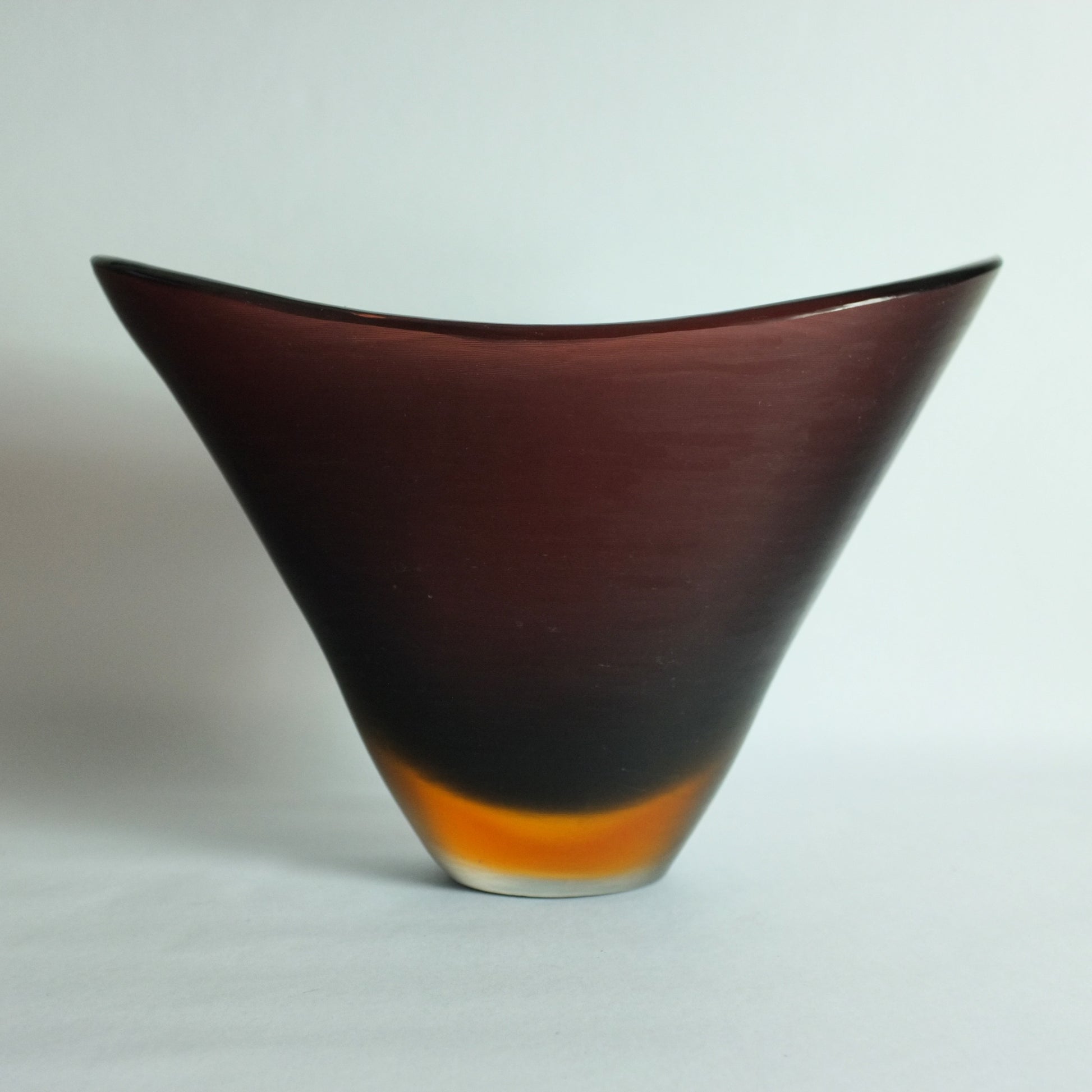 A large flattened V shaped vase with deep "prugnolo" color overlaid in orange and clear and featuring fine etched lines across the surface.