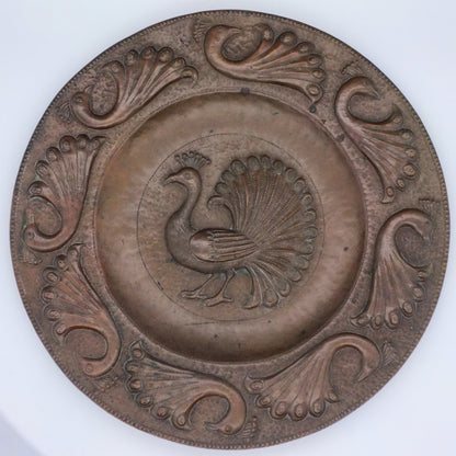 A copper charger with a central motif of a standing peacock, surrounded by eight stylized peacock designs around the edge.