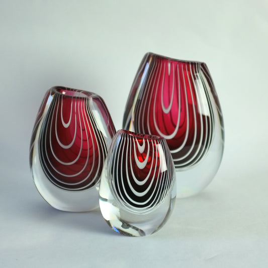 A set of three asymmetric Zebra vases in red with white thread decoration.