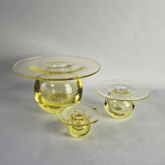 A set of three yellow glass vases of graduating size featuring a wide flat rim above a spherical body.