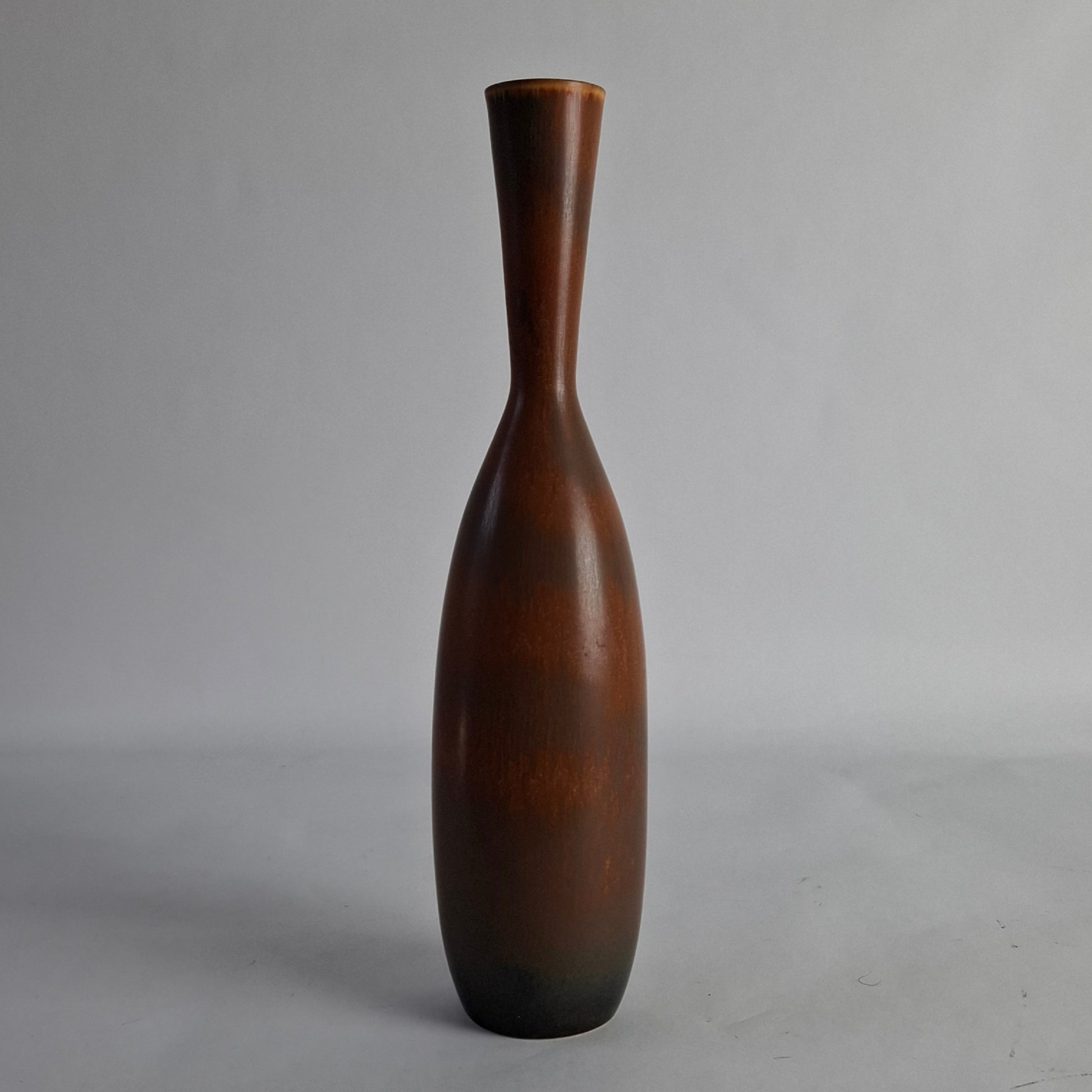 A tall, brown stoneware vase designed by Carl-Harry Stalhane.