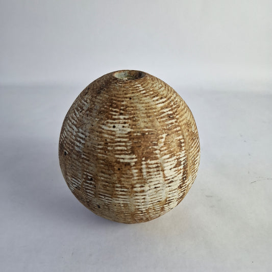A spherical brown seed pod vase with textured surface.