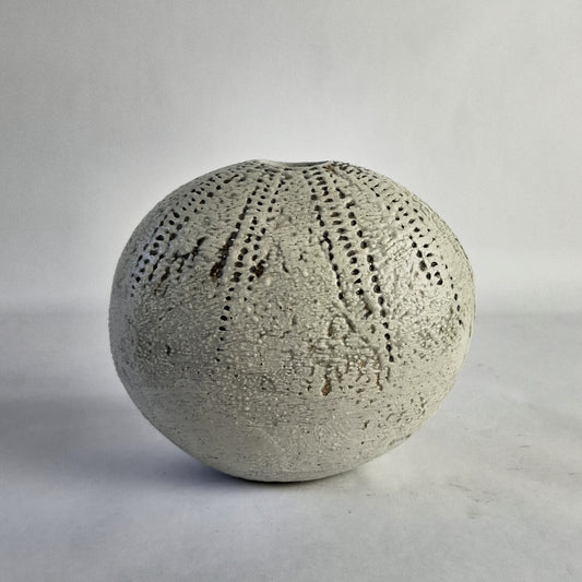 A white, egg-shaped ceramic vase with dot patterns and a textured surface.