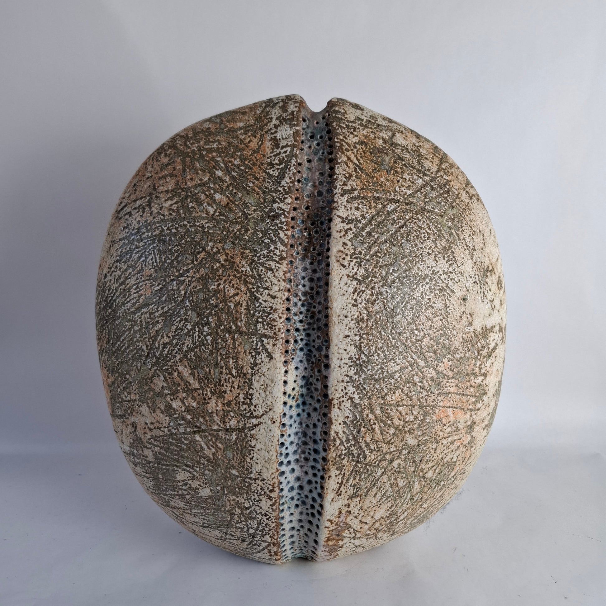A monumental  flattened ovoid stoneware vase with central vertical groove and heavily textured and glazed surface.
