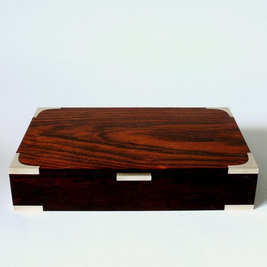 A rectangular box made of rosewood with silver detailing.