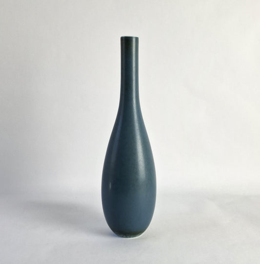 A tall unique stoneware vase with a blue glaze.