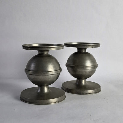 A pair of pewter candlesticks with a spherical design.