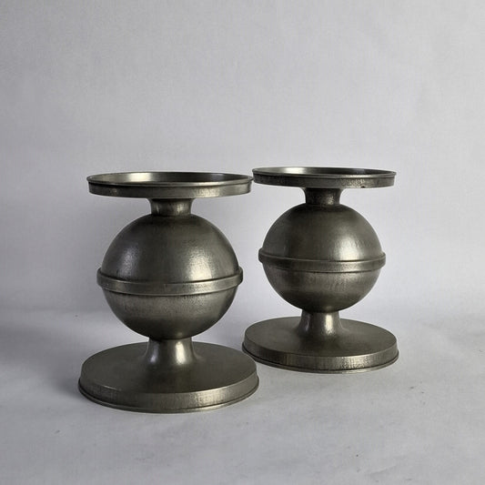 A pair of pewter candlesticks with a spherical design.