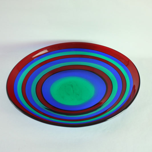 A large, round glass bowl with alternating red, blue, and green bands.