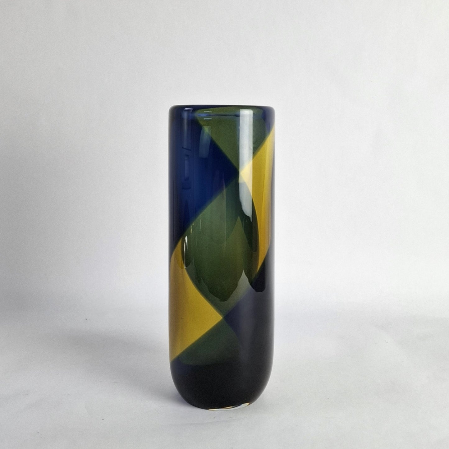 A cylindrical glass vase with a wide banded spiral design in blue and yellow.