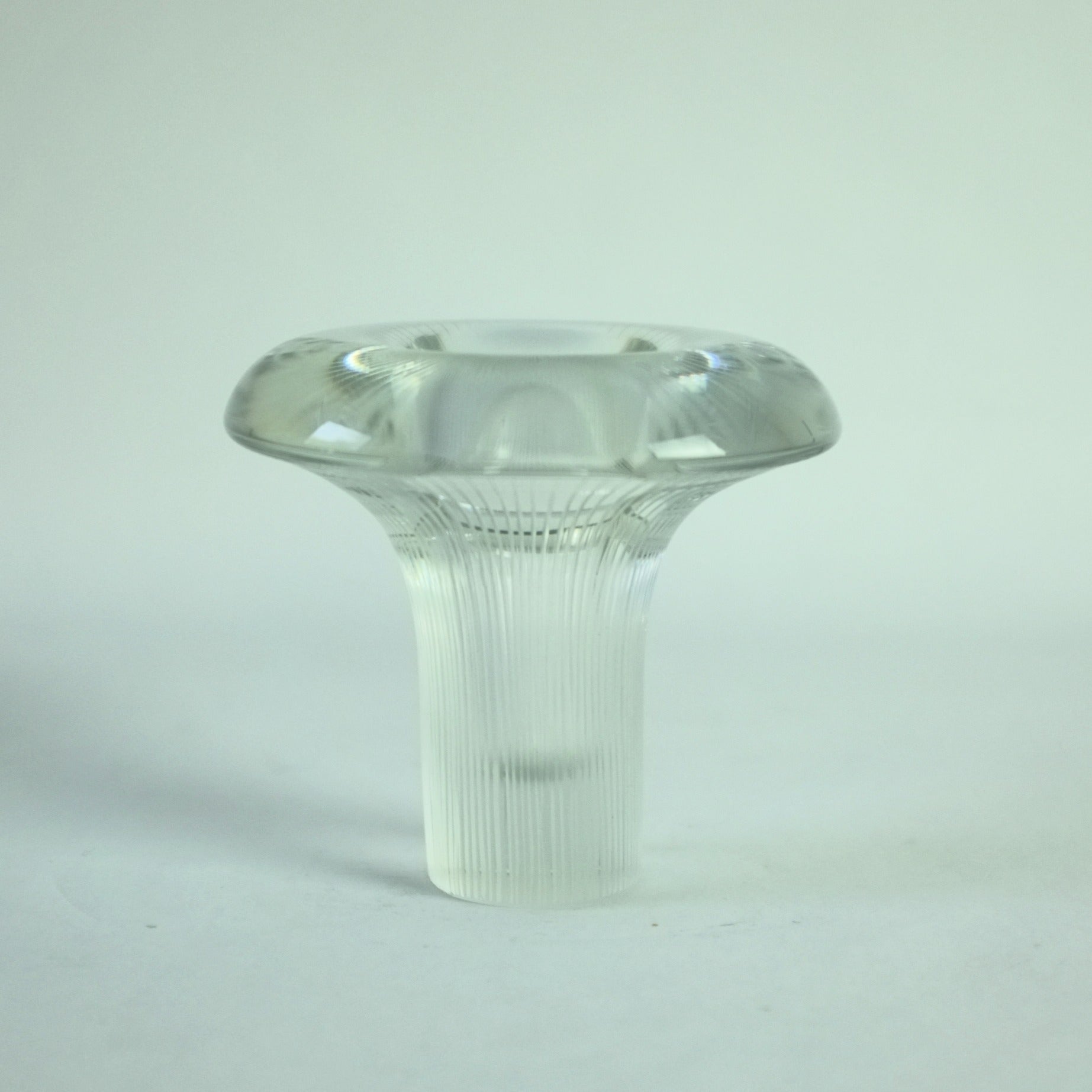 A clear glass vase with vertical lines engraved from the base to the rim, displaying a distinctive shape of a mushroom.