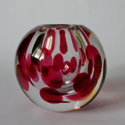 A heavy round clear glass vase with a pattern of internal red spots.